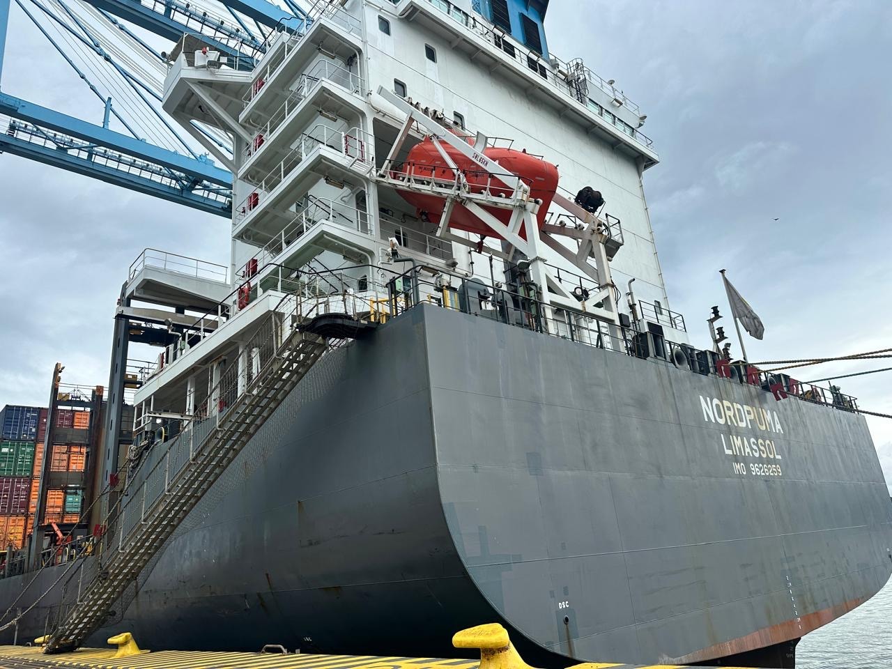 Commercial cargo vessel Nordpuma berthed at container terminal under port cranes
